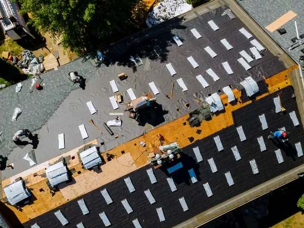 About Us: Workers installing a new roof while organizing materials on the surface