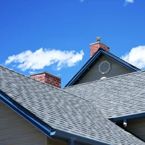 About Us section featuring roofs with shingles and chimneys under a bright blue sky