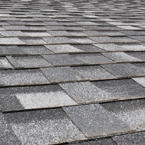 About Us section featuring a textured surface of overlapping gray and black shingles