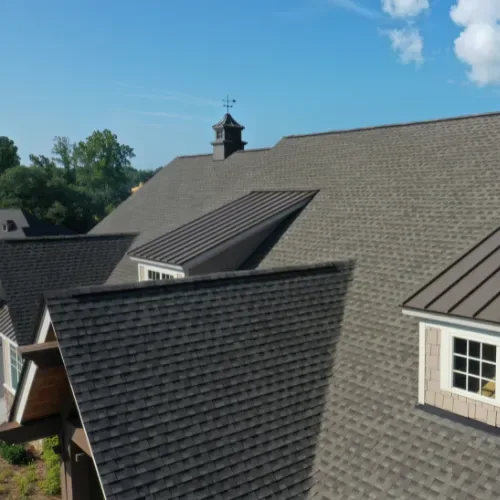 About Us features a sloped roof with grey shingles and a chimney against a clear blue sky