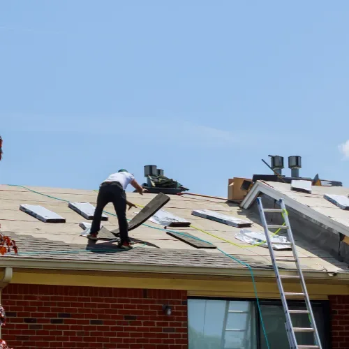 About Us: A worker installs roofing materials on a sloped roof under a clear blue sky