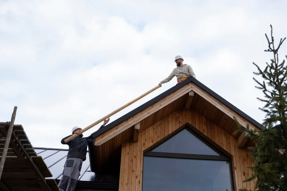 Workers collaborate on siding installation in Okotoks, passing materials efficiently