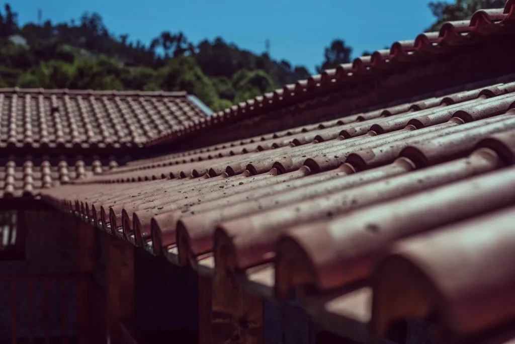 Roofing Okotoks features red-tiled roofs against a clear blue sky landscape